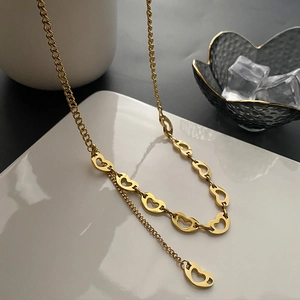 Titanium steel gold heart link necklace with hollow heart charms on a white display tray