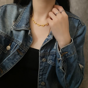 Golden heart-shaped link necklace in titanium steel on a model with denim jacket