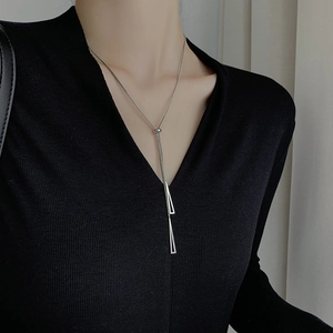 Minimalistische silberne geometrische Y-Halskette mit Dreieck-Quasten auf schwarzem Pullover