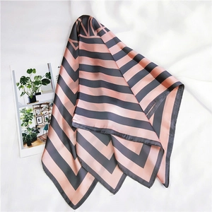 Detail view of pink and grey striped square silk scarf on a white fabric background