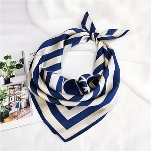 Detail of navy and cream striped silk scarf tied in a bow on a white fabric background