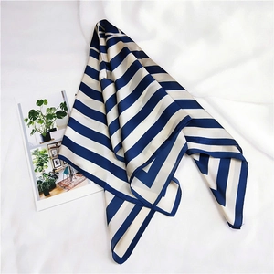 Detailed view of striped satin silk scarf displayed on fabric with a magazine