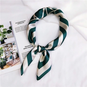 Detail of a green striped square silk scarf with geometric V-patterns and satin finish
