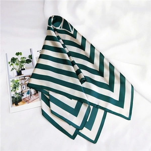 Close-up of green and cream striped satin square scarf on white fabric background