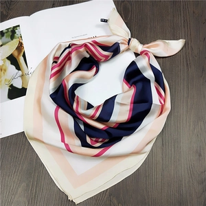 Detail of navy and pink striped silk scarf with elegant knot on a wooden surface