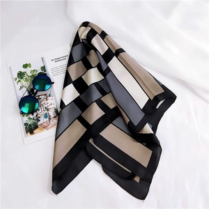Detail of a geometric square scarf with satin texture displayed with sunglasses