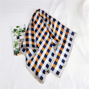 Detail of silk-like square scarf featuring classic orange and navy blue grid pattern