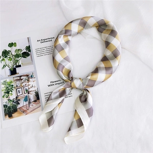 Detailed shot of yellow and grey plaid satin scarf on white wrinkled fabric