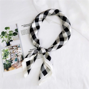 Close-up of a classic black and white checkered chiffon square scarf tied in a stylish knot