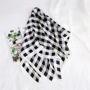 Detailed view of the smooth black and white checkered silk scarf on a white background