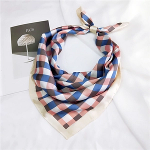 Detailed view of a pink and blue plaid silk scarf styled with a knot on white fabric