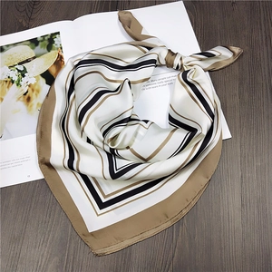 Detailed view of striped satin square scarf with elegant geometric patterns on a magazine