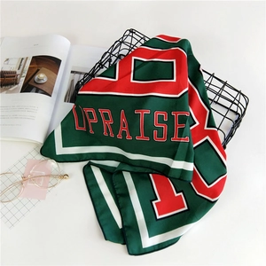 Detailed view of satin scarf with green red white letter print on a stylish metal basket