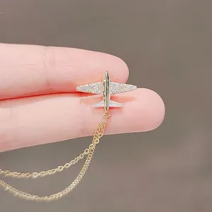 Macro shot of gold airplane brooch with sparkling zircons and delicate double tassel chains