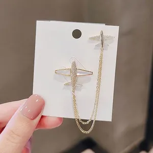 Detailed shot of gold airplane earrings with shell wings and dangling chains