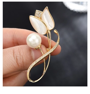 Nahaufnahme der Tulpenbrosche mit weißen Muschelblüten und einer großen Perle