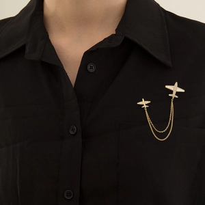 Cute gold airplane brooch with pearl shell and tassel chains on a black shirt