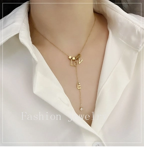 Detail of gold Y-shaped titanium steel necklace with LOVE charms and a small zircon pendant