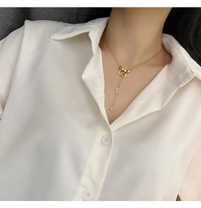 Detail view of a gold LOVE letter necklace with a sparkling rhinestone on a model