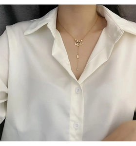 Detail view of a gold Y-shaped necklace with LOVE letter pendant and a small rhinestone