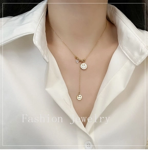Détail d'un collier en Y doré avec deux pendentifs smiley porté par un mannequin femme