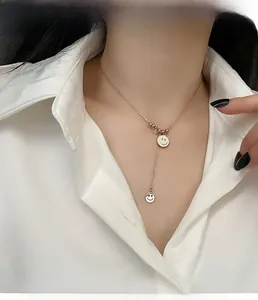 Détail du collier superposé or rose avec deux pendentifs smiley sur le mannequin