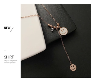 Détail du collier visage souriant en or rose sur fond géométrique minimaliste