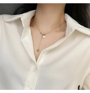Détail du collier en Y doré en titane avec pendentif sourire et cristal de zircon