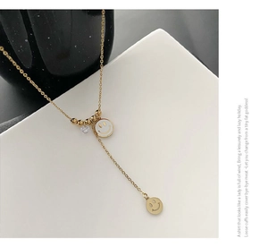 Détail du collier sourire en titane doré avec doubles pendentifs et zircon brillant