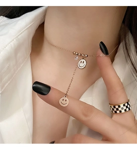 Détail du collier sourire en or rose avec zircon et bague en damier sur le modèle