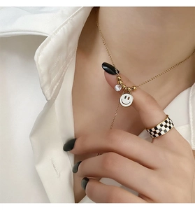 Gros plan du collier avec pendentif smiley doré et bague à damier sur le mannequin