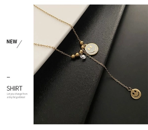 Détail du collier en titane doré avec deux pendentifs smiley et un zircon étincelant