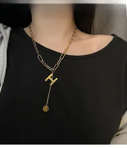 Close-up of golden letter H pendant necklace on model with industrial chain link