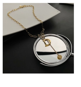 Detail view of gold letter D pendant with thick curb chain and long tassel element