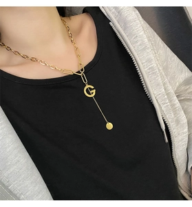 Detailed view of gold G-letter pendant necklace with layered chain on a model
