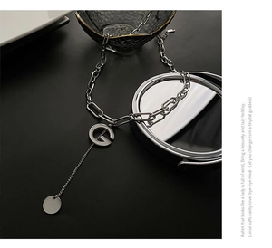Macro view of silver titanium steel G-letter pendant necklace with polished round charm
