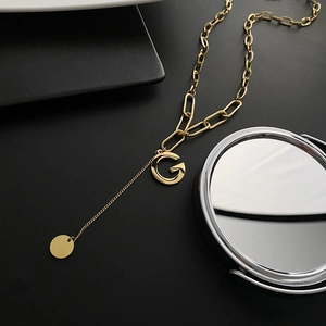 Golden titanium steel paperclip chain necklace with a letter G pendant on black background