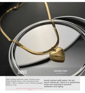 Detailed view of gold heart pendant with Love You More engraving on snake chain necklace