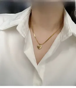 Close-up of gold heart pendant with Love You More engraving on a flat snake chain