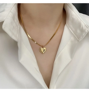 Close-up of 18K gold-plated heart pendant on a stylish herringbone chain for women