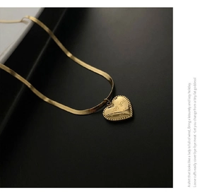 Macro shot of gold heart pendant with Love You More engraving on a flat snake chain