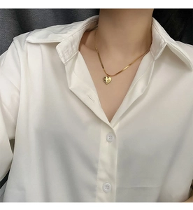 Close-up of a 18K gold-plated heart pendant on a flat snake chain worn by a model