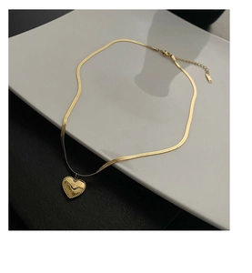 Detail of gold heart pendant with Love you more engraving on a sleek snake chain necklace