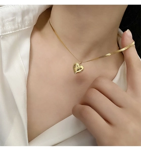 Close-up of a 18K gold-plated heart pendant necklace on a model wearing a white shirt