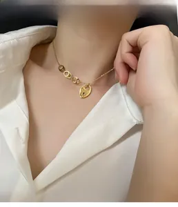 Détail du collier à pendentif porte-bonheur doré porté sur une chemise blanche