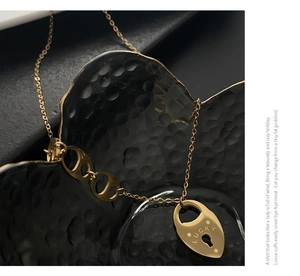 Détail du pendentif Lucky doré en acier titane avec maillons ovales et motif de verrou