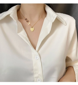 Détail d'un collier en acier titane doré avec pendentif Lucky gravé sur un mannequin