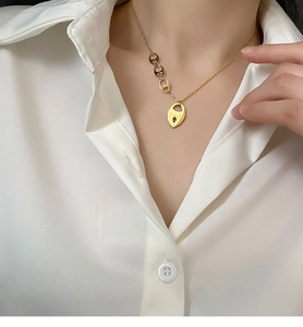Détail du collier cadenas cœur doré en titane avec gravure LUCKY sur chemise en soie