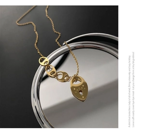 Gros plan d'un pendentif cœur Lucky doré sur une chaîne vintage à gros maillons ovales