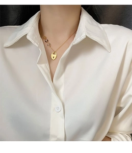 Détail du collier en titane doré avec pendentif cadenas cœur et anneaux décoratifs